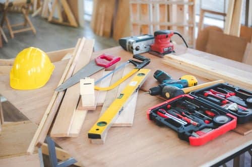 Carpentry tools, hard hat and lumber laid out on a workbench for a home renovation project