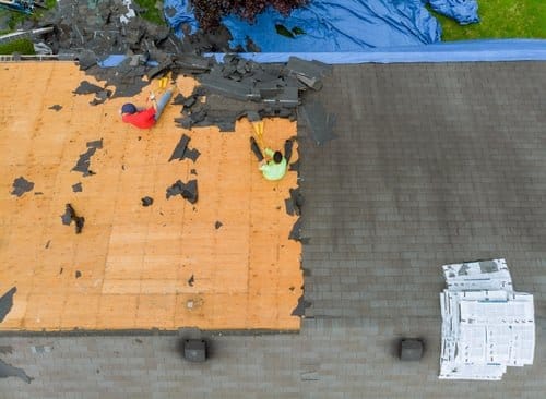 Roofers replacing damaged shingles and exposed decking during a roof repair in Knoxville, TN