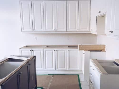 White kitchen cabinets being installed and leveled by Build By Manny in Knoxville, TN